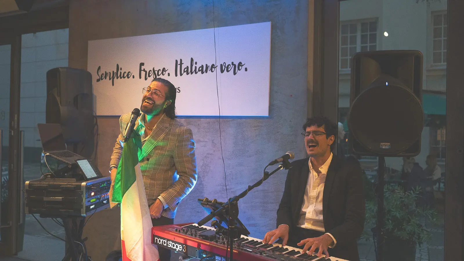 Francesco śpiewa z włoską flagą, Manfredi gra na keyboardzie pod napisem „Semplice. Fresco. Italiano vero.” — Bottegas Canta, ul. Oboźna 9, Warszawa