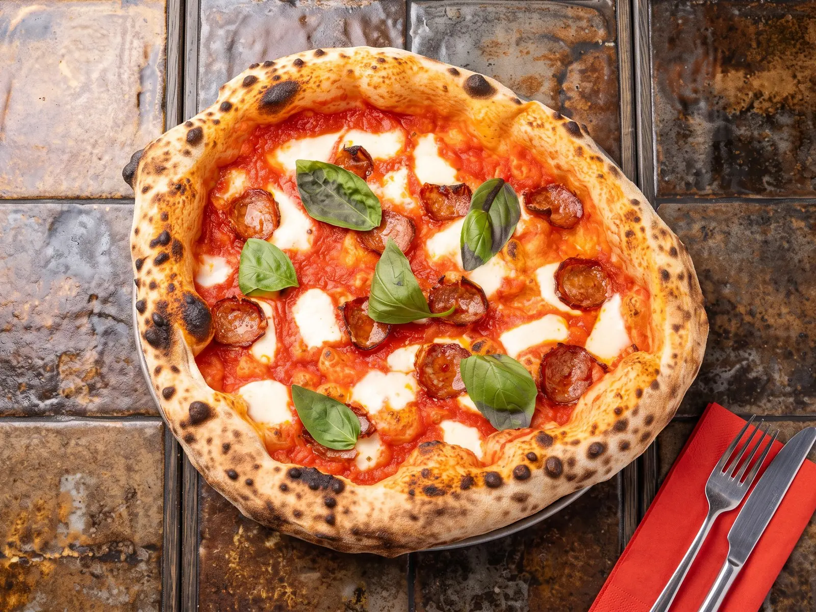 Pizza Diavola z pikantnym salami, mozzarellą i bazylią, z przypieczonym brzegiem — na stole w Bottegas w Warszawie